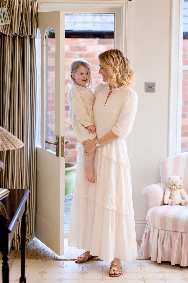 Amy holding her young daughter in a softly lit doorway